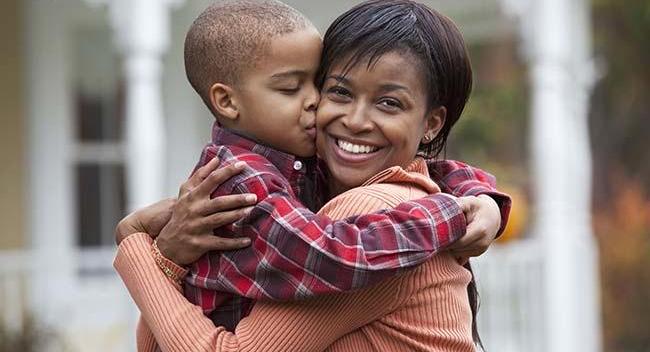 Black mother hugging son outdoors